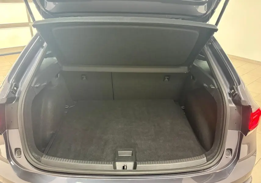 Coffre ouvert vu de l'arrière d'un Volkswagen Taigo gris cendré 2024, montrant l'espace de chargement vide.