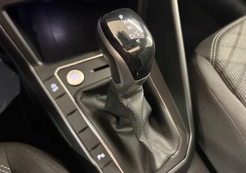 Gros plan sur la commande de boîte automatique noire et grise dans l'habitacle du Volkswagen Taigo gris cendre.
