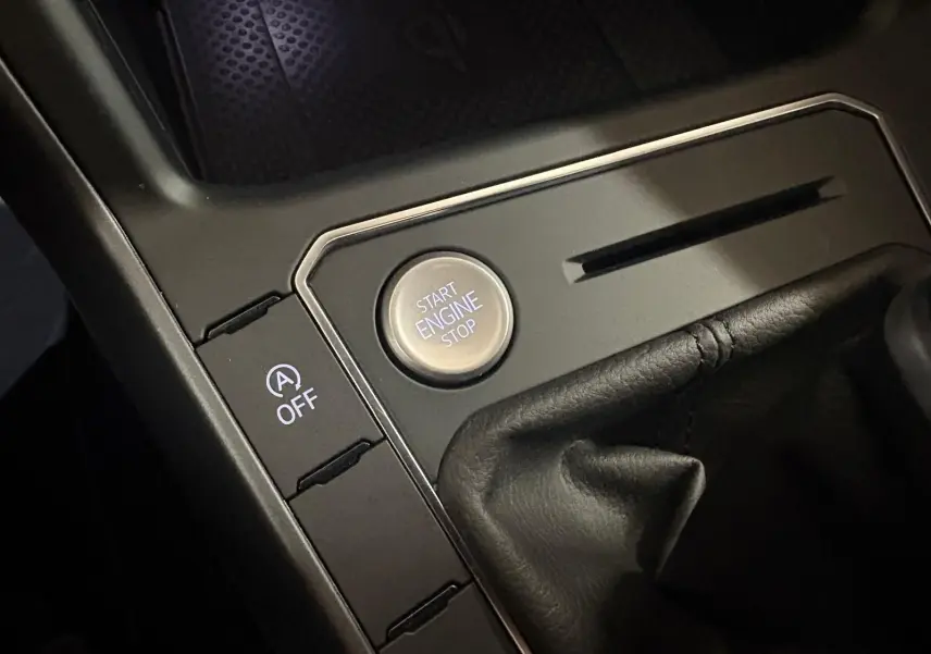 Gros plan sur le bouton start/stop moteur et commande auto start/stop dans la console centrale noire du Volkswagen Taigo.