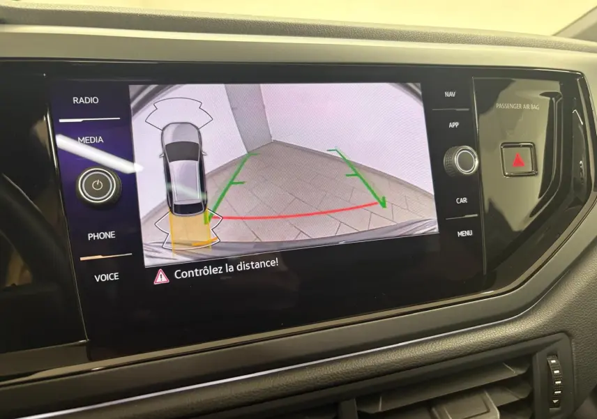 Vue de l'écran central affichant la caméra de recul du Volkswagen Taigo gris cendré avec alertes de distance.