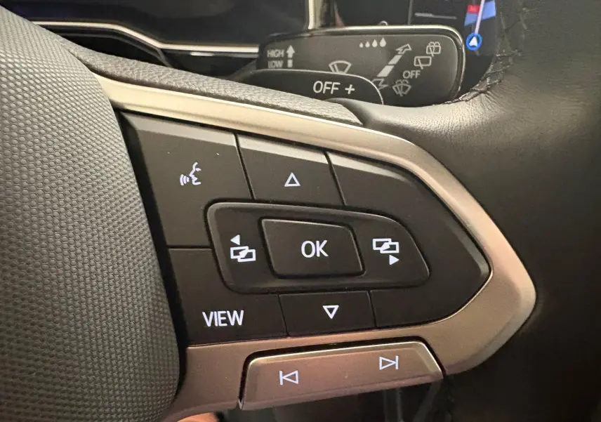 Gros plan sur les commandes au volant du Volkswagen Taigo gris cendré, avec boutons multifonctions rétroéclairés.