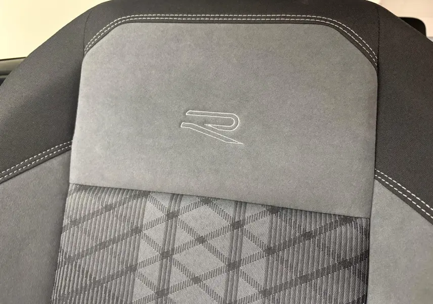 Détail du siège avant gris avec surpiqûres blanches et logo R brodé, intérieur Volkswagen Taigo 2024.