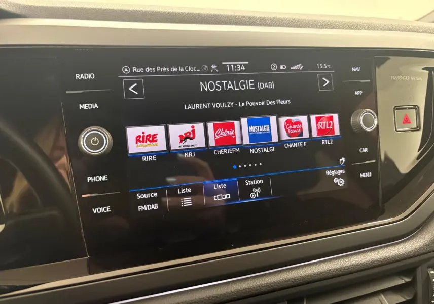 Écran tactile central du Volkswagen Taigo 2024 affichant les stations radio DAB, avec commandes autour et finition noire brillante.