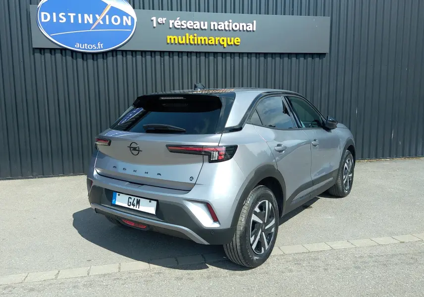 Vue 3/4 arrière droite d'un Opel Mokka Electric gris 2025, avec toit noir et feux arrière LED fins.