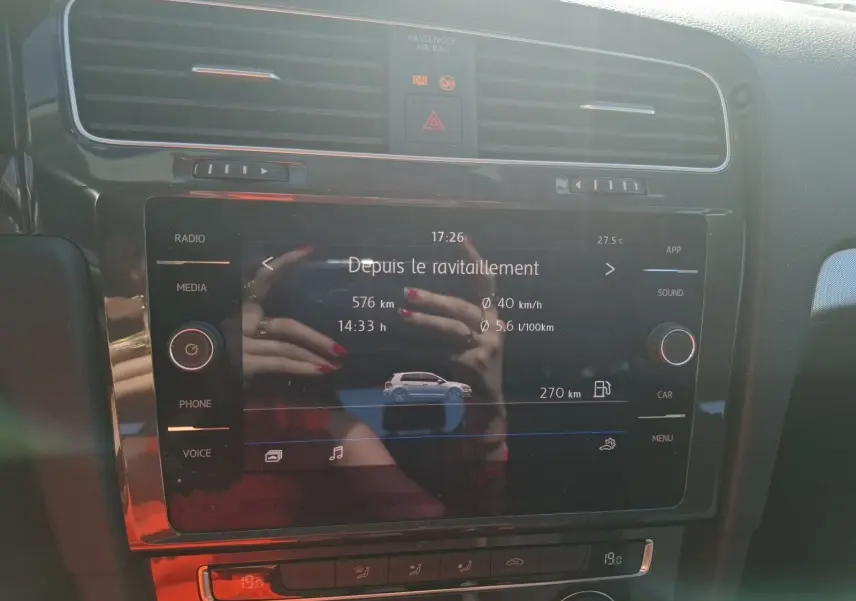 Écran tactile central de la Volkswagen Golf blanc, affichant les données de consommation et autonomie, vue de face intérieure.