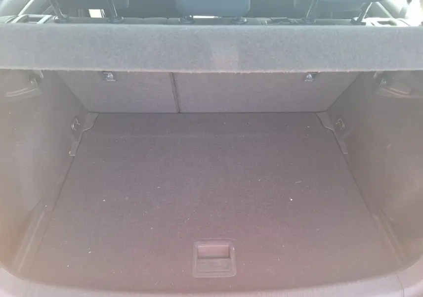 Coffre ouvert d’une Volkswagen Golf blanche 2019, vue de l’arrière, montrant un espace de chargement vide et propre.