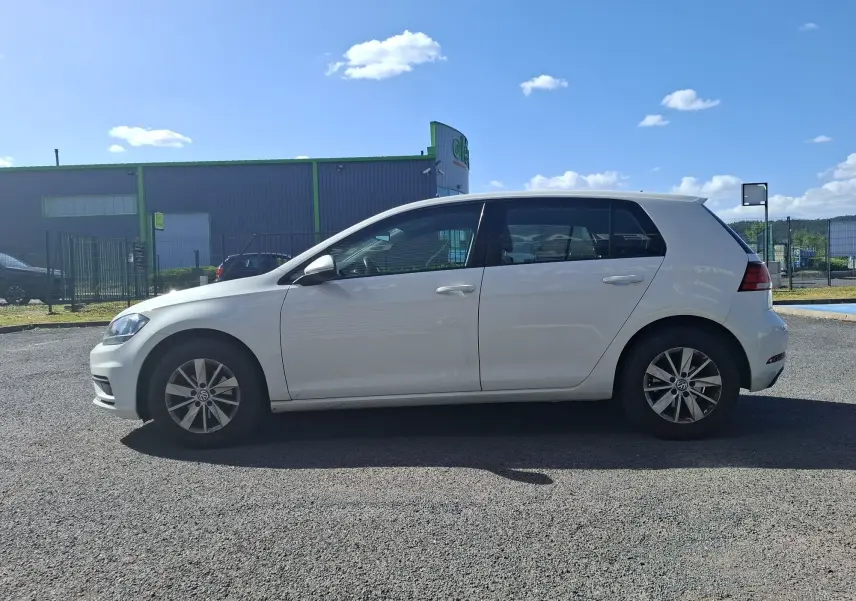 Volkswagen Golf blanc vue de profil côté gauche, avec jantes alliage et vitres teintées, stationnée en extérieur.