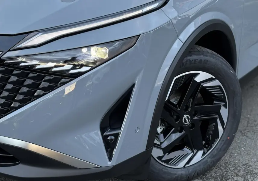 Gros plan sur l'avant droit du Nissan Qashqai gris Ceramic, mettant en valeur le phare LED et la jante alliage noire et argent.