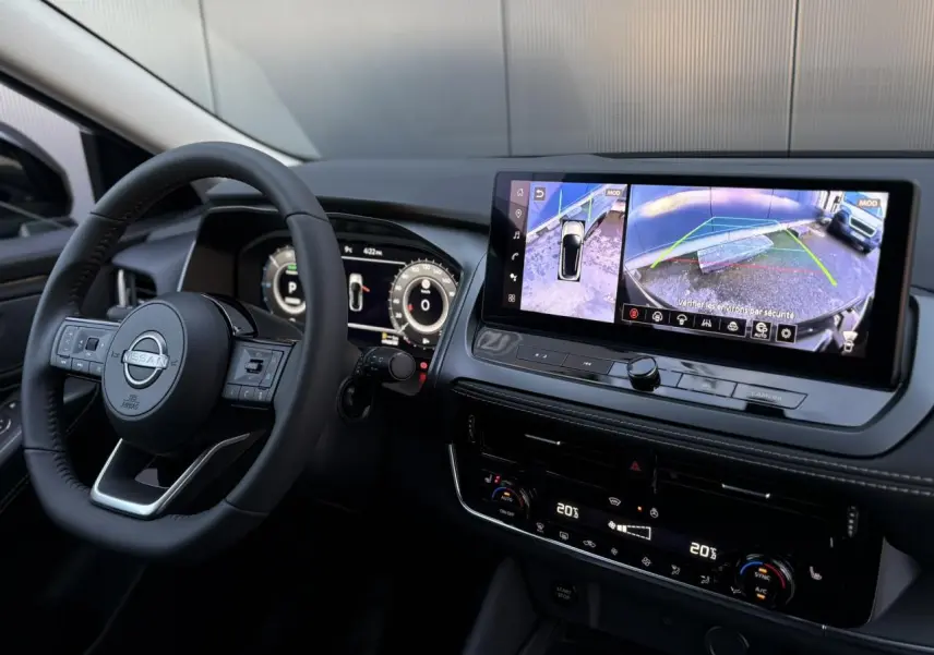 Vue intérieure du tableau de bord et volant du Nissan Qashqai 2025 avec écran tactile affichant la caméra 360° et instrumentation numérique.