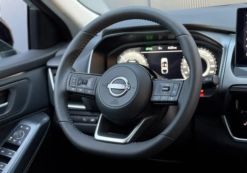 Vue rapprochée du volant cuir noir du Nissan Qashqai 2025 avec commandes intégrées et tableau de bord numérique.