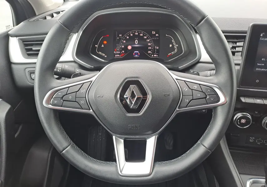 Vue rapprochée du volant noir du Renault Captur 1.3 TCE 140 Intens 2022 avec tableau de bord digital et commandes intégrées.