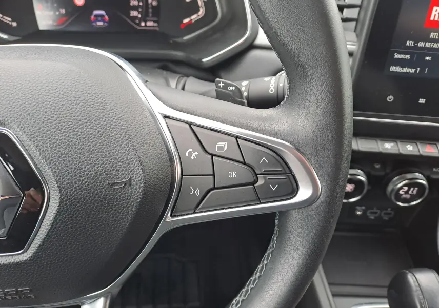 Gros plan sur le volant noir du Renault Captur 2022, montrant les commandes multifonctions à droite et le tableau de bord numérique.