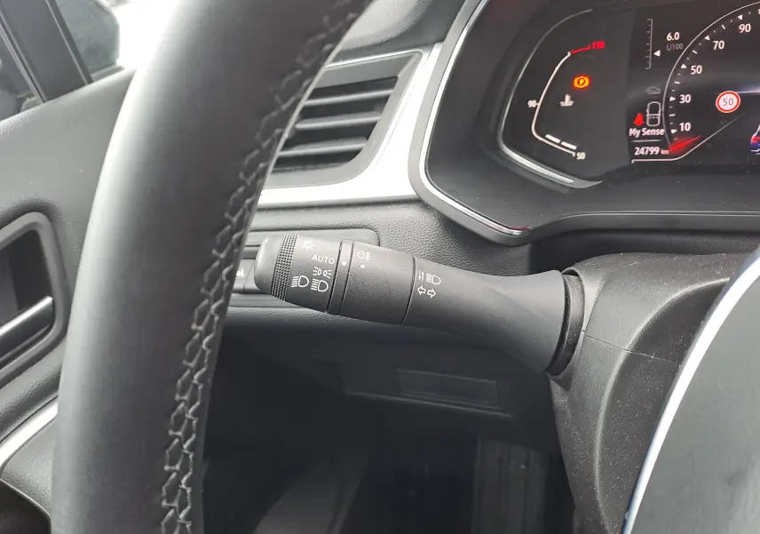 Vue rapprochée du commodo d'éclairage à gauche du volant dans l'habitacle noir du Renault Captur bleu marine 2022.