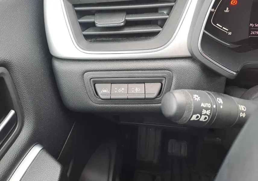 Détail intérieur côté gauche du tableau de bord du Renault Captur bleu marine 2022, avec commandes d'aide à la conduite et éclairage.