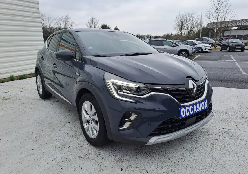 Renault Captur bleu marine 2022 en 3/4 avant droit, avec phares LED et plaque "OCCASION" visible.
