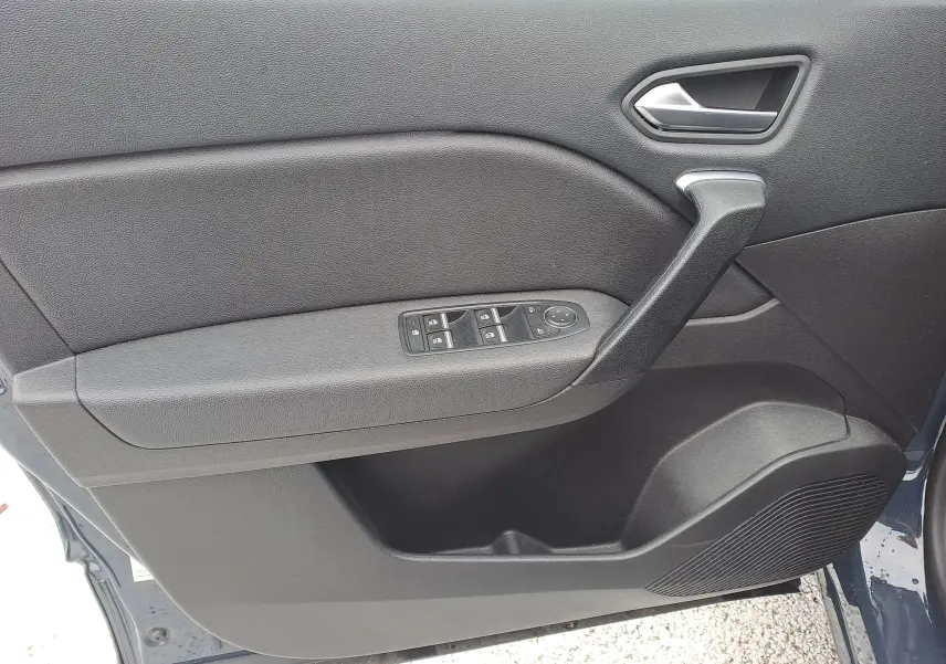 Vue intérieure côté gauche de la porte avant d'un Renault Captur bleu marine, avec commandes de vitres et poignée intégrée.
