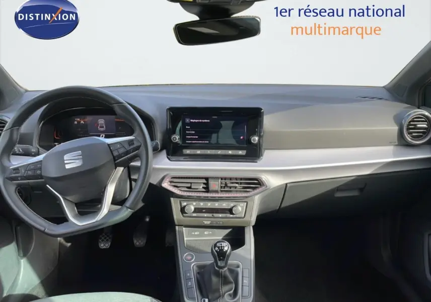 Vue intérieure frontale du tableau de bord de la SEAT Ibiza bleu Fjord 2025 avec volant multifonction et boîte manuelle.