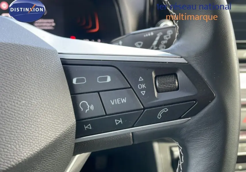 Gros plan sur les commandes multifonctions côté gauche du volant en cuir noir d'une SEAT Ibiza bleu Fjord 2025.