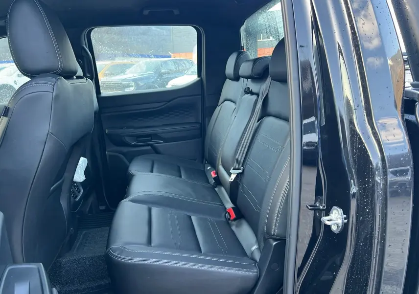 Vue intérieure côté droit sur la banquette arrière en cuir noir du Ford Ranger 2025 noir agate avec portière ouverte.