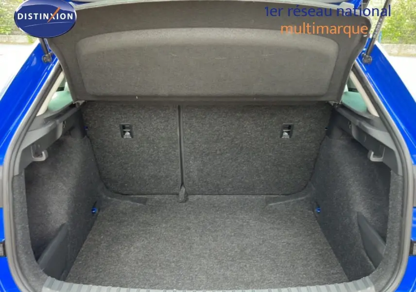 Coffre ouvert vu de l’arrière d’une Skoda Scala 2025 en bleu racing metal, intérieur du coffre en tissu gris.