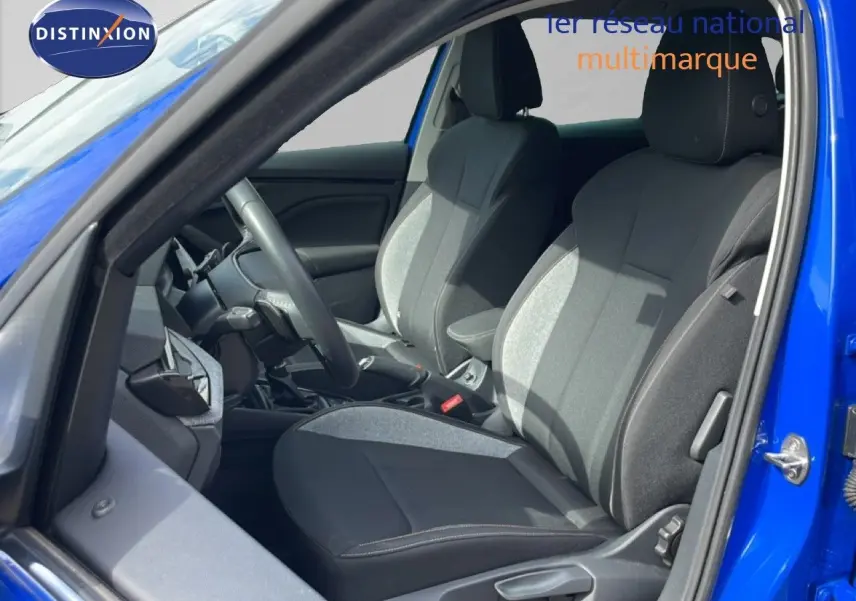Vue intérieure côté conducteur d'une Skoda Scala bleu racing metal, sièges tissu gris et noir avec volant multifonction.