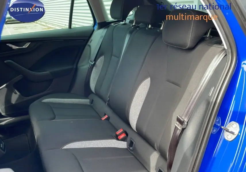 Vue intérieure sur la banquette arrière en tissu gris et noir d'une Skoda Scala bleu racing, porte arrière ouverte côté droit.