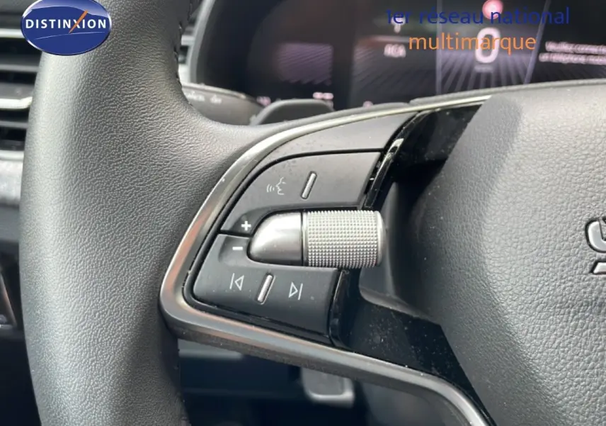 Gros plan sur les commandes gauche du volant d’une Skoda Scala 2025, volant en cuir noir avec molette crantée.