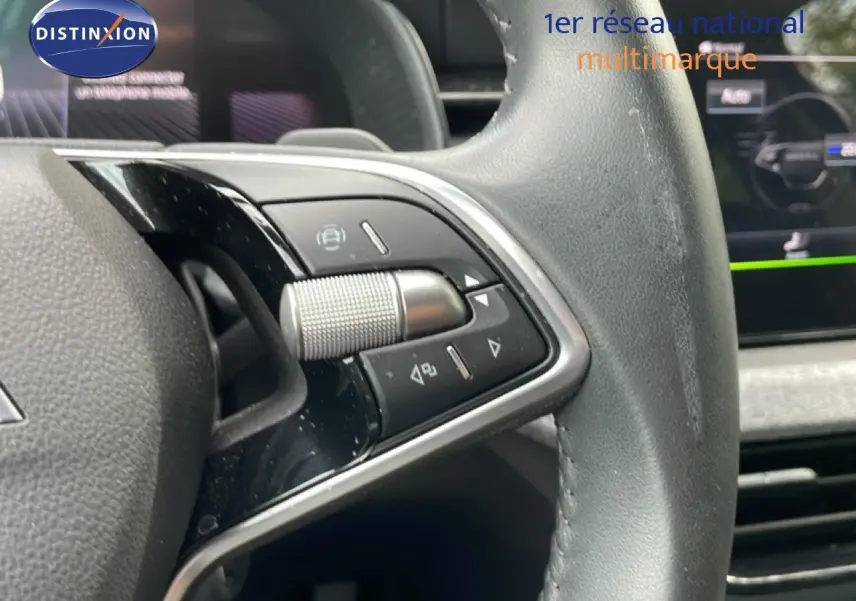 Gros plan sur la partie gauche du volant cuir de la Skoda Scala 2025 avec commandes multifonctions et tableau de bord flou en arrière-plan.
