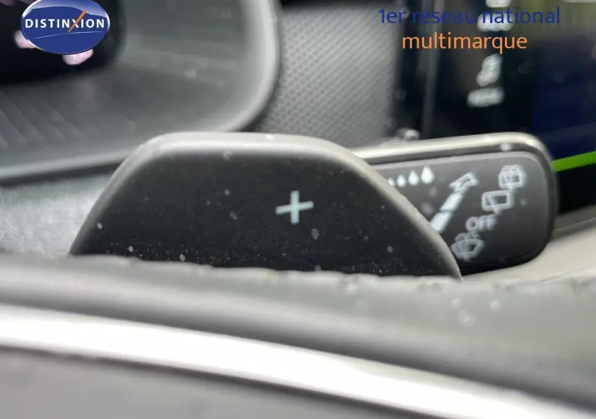 Gros plan sur la palette de changement de vitesse "+" côté droit du volant dans l'habitacle d'une Skoda Scala bleu Racing Metal.