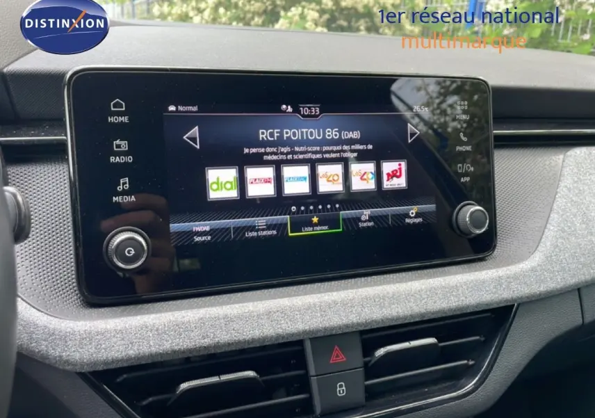 Écran tactile central de la Skoda Scala 2025, affichant les stations radio, avec tableau de bord gris clair texturé.