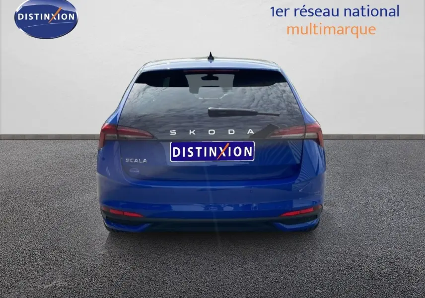 Vue arrière d'une Skoda Scala bleu racing metal avec feux arrière étirés et logo distinctif sur fond neutre.