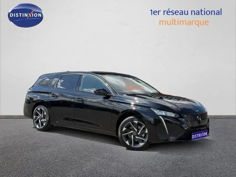 Peugeot 308 SW hybride noire vue en 3/4 avant droit, avec jantes alliage et calandre distinctive.