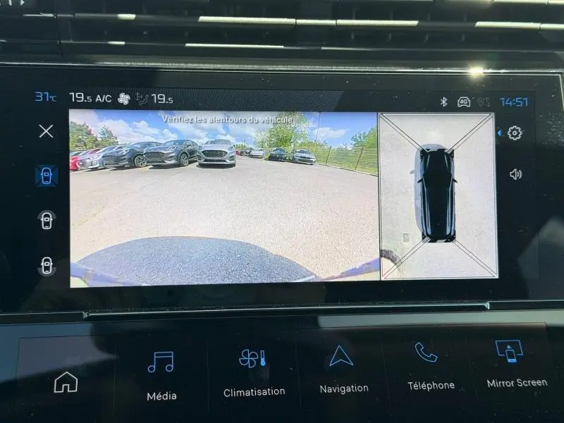 Vue écran multimédia montrant la caméra de recul et la vue 360° du Peugeot 308 SW noir Perla Nera, stationné en extérieur.