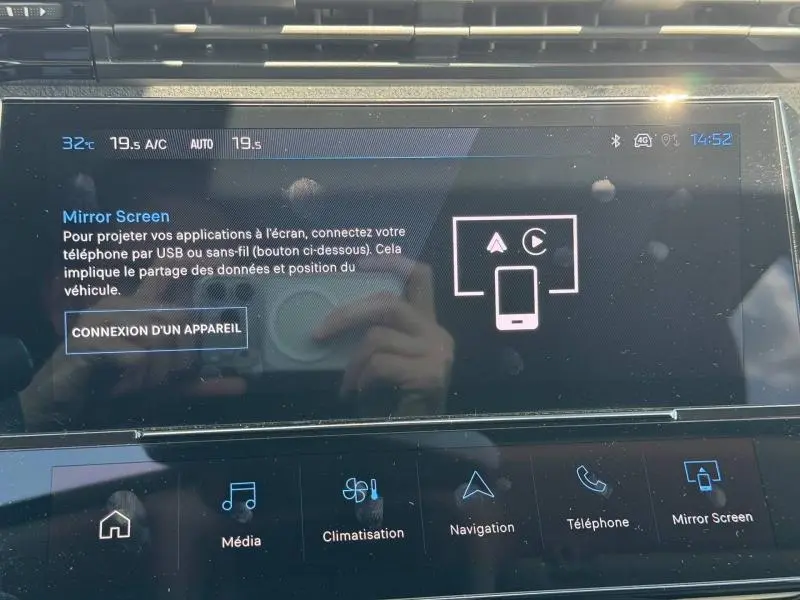 Écran tactile intérieur du Peugeot 308 SW 2025 affichant les options Mirror Screen et climatisation, avec reflets visibles.