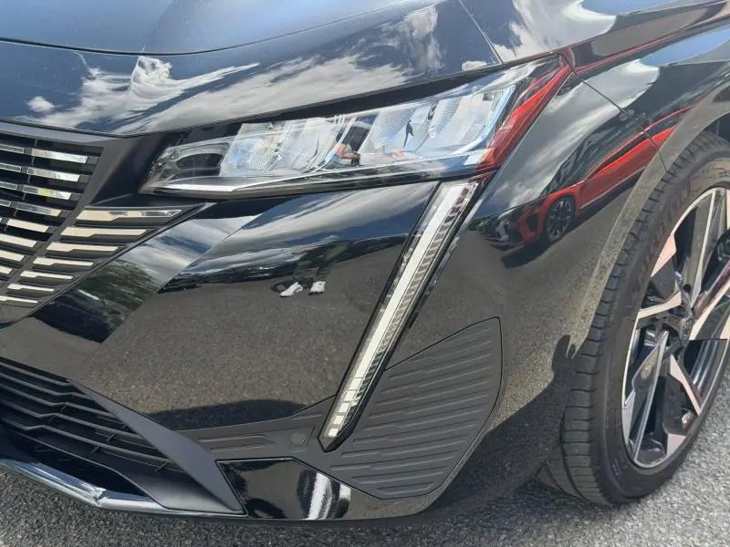 Gros plan sur l'avant droit noir Perla Nera du Peugeot 308 SW 2025, mettant en valeur le phare LED et la calandre distinctive.
