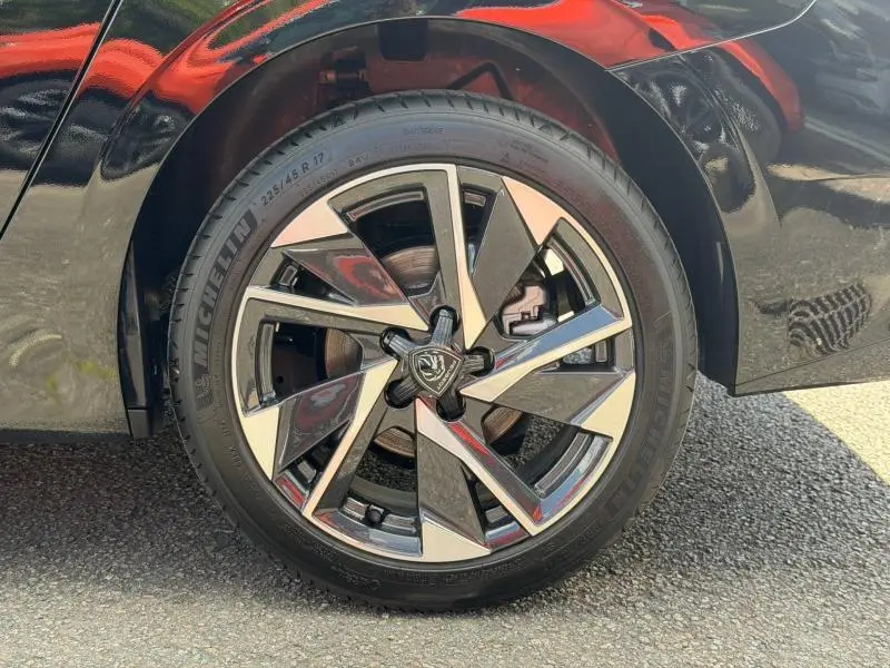 Gros plan sur la roue avant gauche du Peugeot 308 SW 1.2 Hybrid 145ch Allure 2025 en Noir Perla Nera avec jante alliage bicolore.