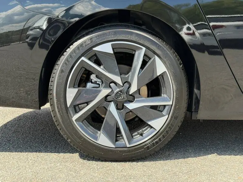 Gros plan sur la roue arrière droite d'une Peugeot 308 SW 1.2 Hybrid 145ch Allure en noir Perla Nera, jante alliage stylisée.