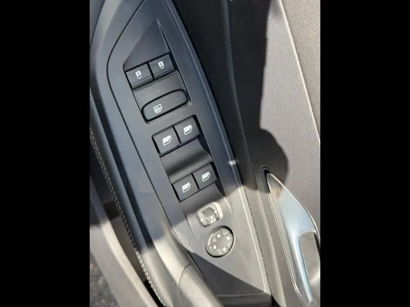 Gros plan sur les commandes de lève-vitres et rétroviseurs côté conducteur du Peugeot 308 SW 2025 noir Perla Nera.