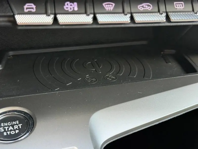 Détail intérieur du plateau de recharge sans fil et bouton Start/Stop sur la console de la Peugeot 308 SW noire.