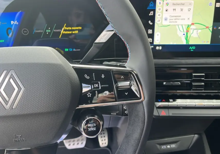 Vue rapprochée du volant cuir multifonctions de la Renault Clio 6 E-Tech 160 Esprit Alpine avec commandes et écran tactile visible.