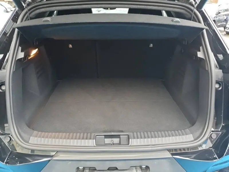 Coffre ouvert vu de l'arrière d'une Renault SYMBIOZ 1.6 E-Tech noir étoilé, espace de chargement vide et éclairé.