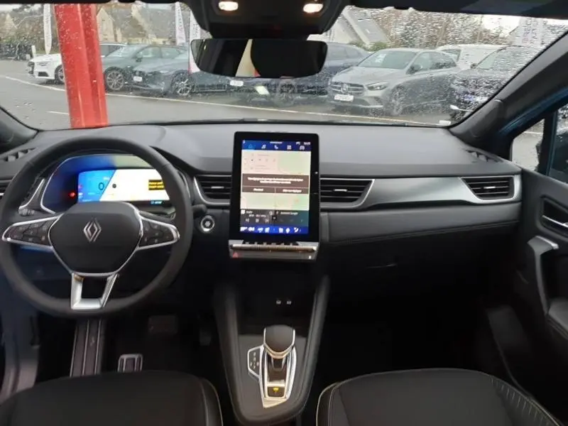 Vue intérieure avant du Renault SYMBIOZ 2025 noir étoilé, avec tableau de bord numérique et écran tactile vertical central.