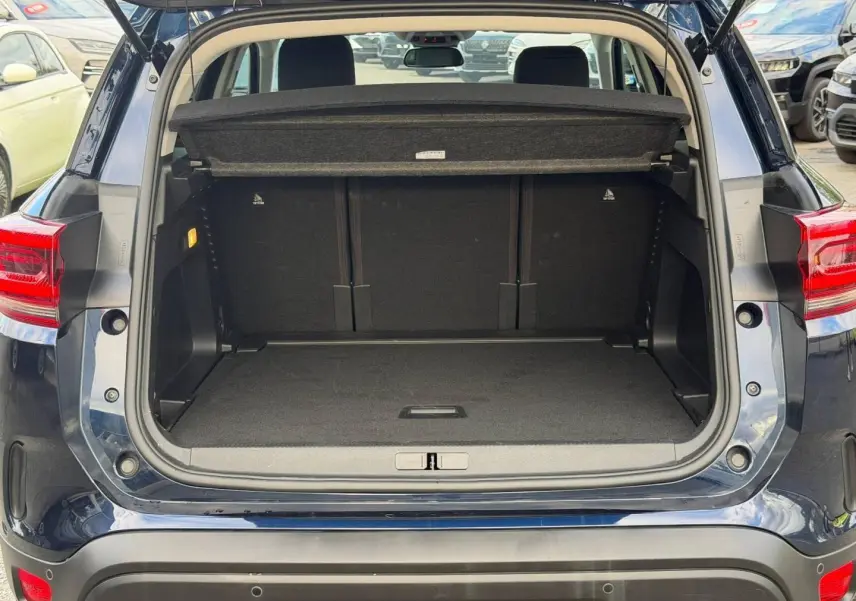 Coffre ouvert vu de l'arrière du Citroën C5 Aircross Bleu Eclipse avec cache-bagages et banquette arrière visible.