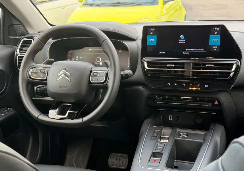 Vue intérieure du poste de conduite du Citroën C5 Aircross 2025, volant cuir et écran tactile central noir.