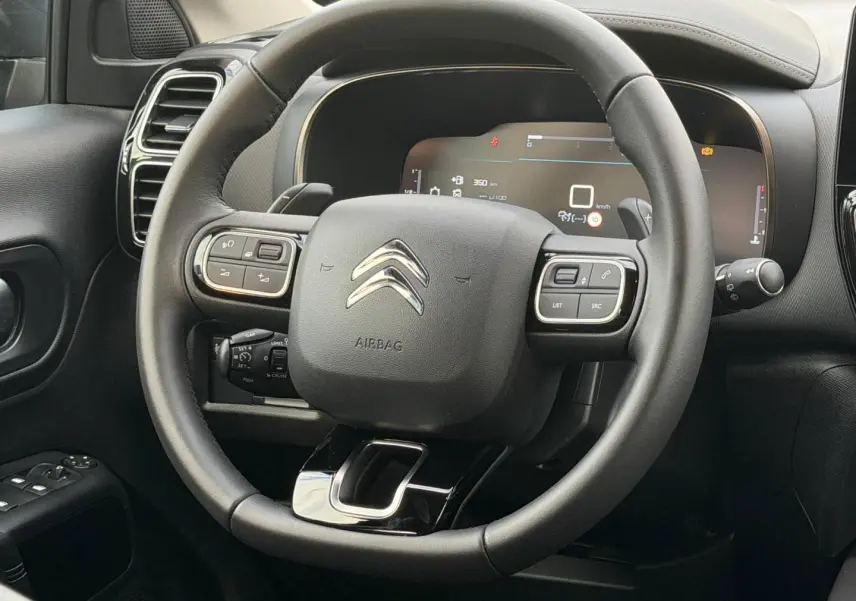 Vue rapprochée du volant cuir multifonction noir du Citroën C5 Aircross 2025 avec tableau de bord numérique.