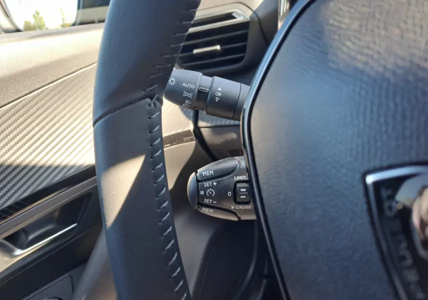 Gros plan sur la commande de régulateur de vitesse et les commandes d'éclairage du côté gauche du volant d'un Peugeot 2008.