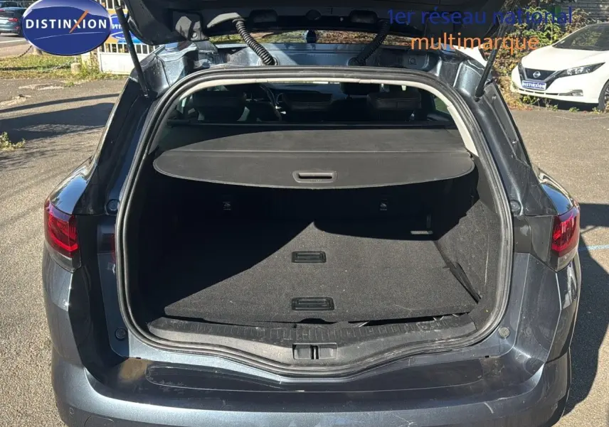 Coffre ouvert vu de l'arrière d'une Renault Mégane Break gris titanium métal, montrant l'espace de chargement vide.