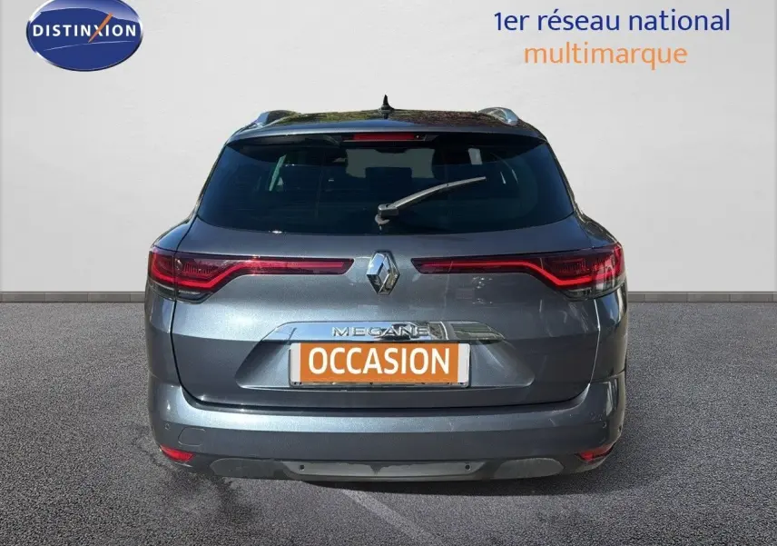 Vue arrière d'une Renault Mégane Break gris titanium métal avec feux LED et logo central visible.