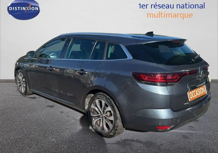 Renault Mégane Break gris titanium métal vue 3/4 arrière droit avec jantes alliage et feux LED allumés.