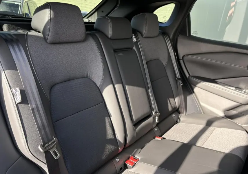 Vue intérieure côté droit des sièges arrière gris et noirs du Nissan Qashqai III e-Power 2025 avec ceintures de sécurité visibles.